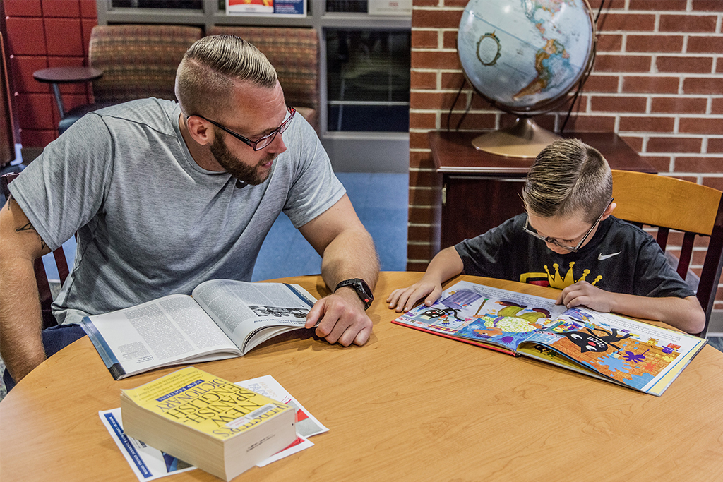 man and son reading in library