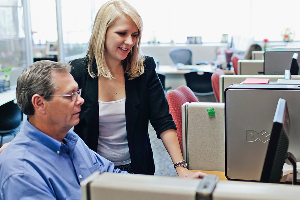 woman instruction man at computer