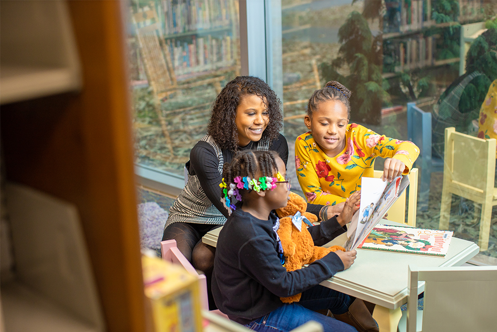 courtney reading a book with two kids in a classroom