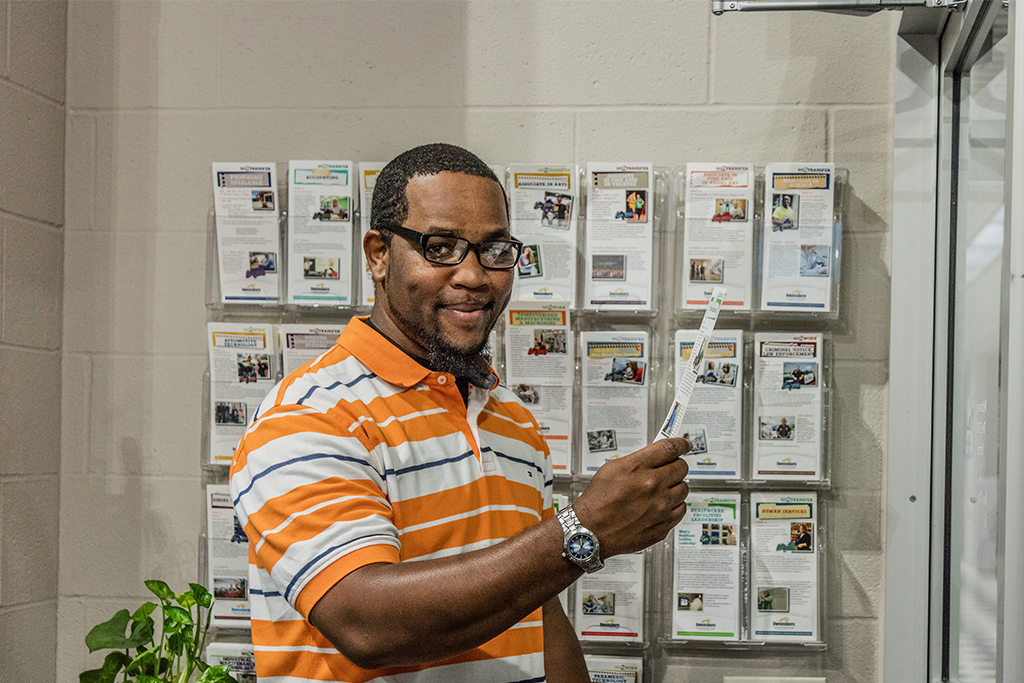 OCTC student holding a pamphlet smiles at the camera