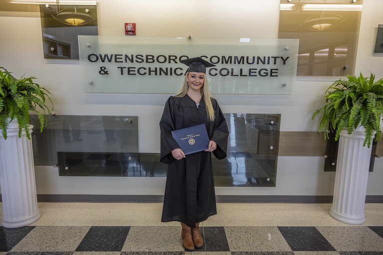 woman in cap and gown posing with her degree