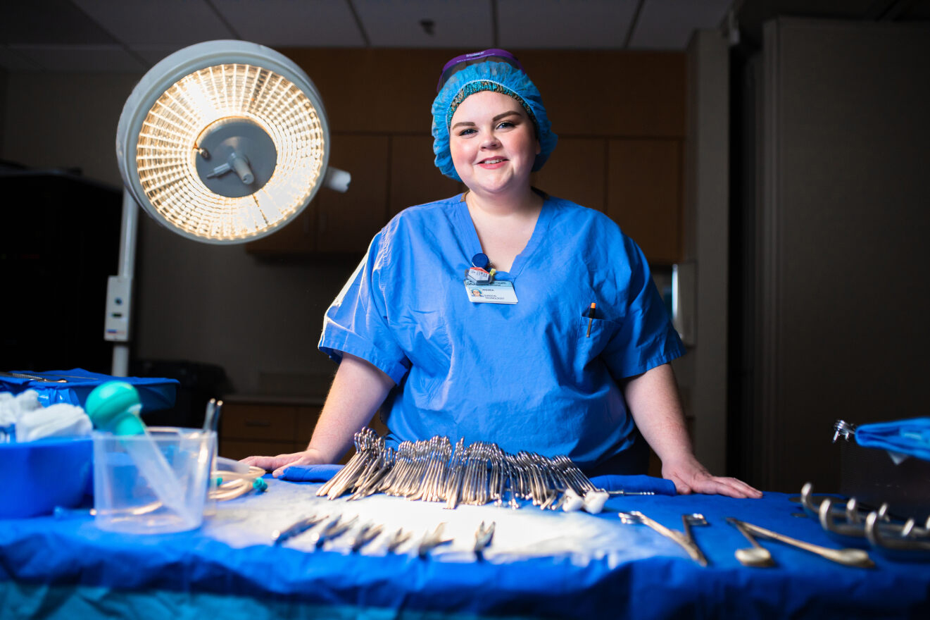 Surgical Technology student standing behind a table of surgical instraments.